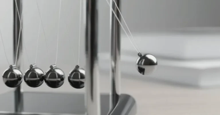 Newton's cradle illustrating momentum, symbolizing building positive study momentum for CFA exams.