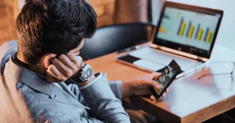 CFA candidate distracted by smartphone while studying, illustrating procrastination during exam preparation.
