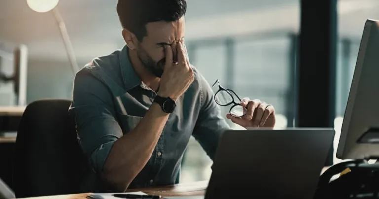 Stressed CFA candidate at a computer, struggling with fear and procrastination during exam preparation.