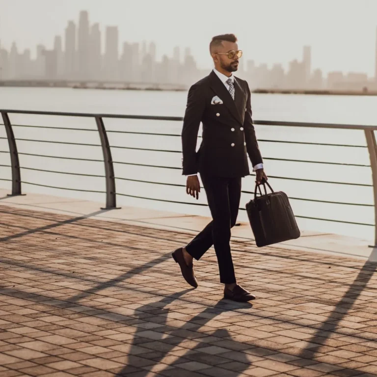 Stylish man in suit walking by city waterfront with briefcase