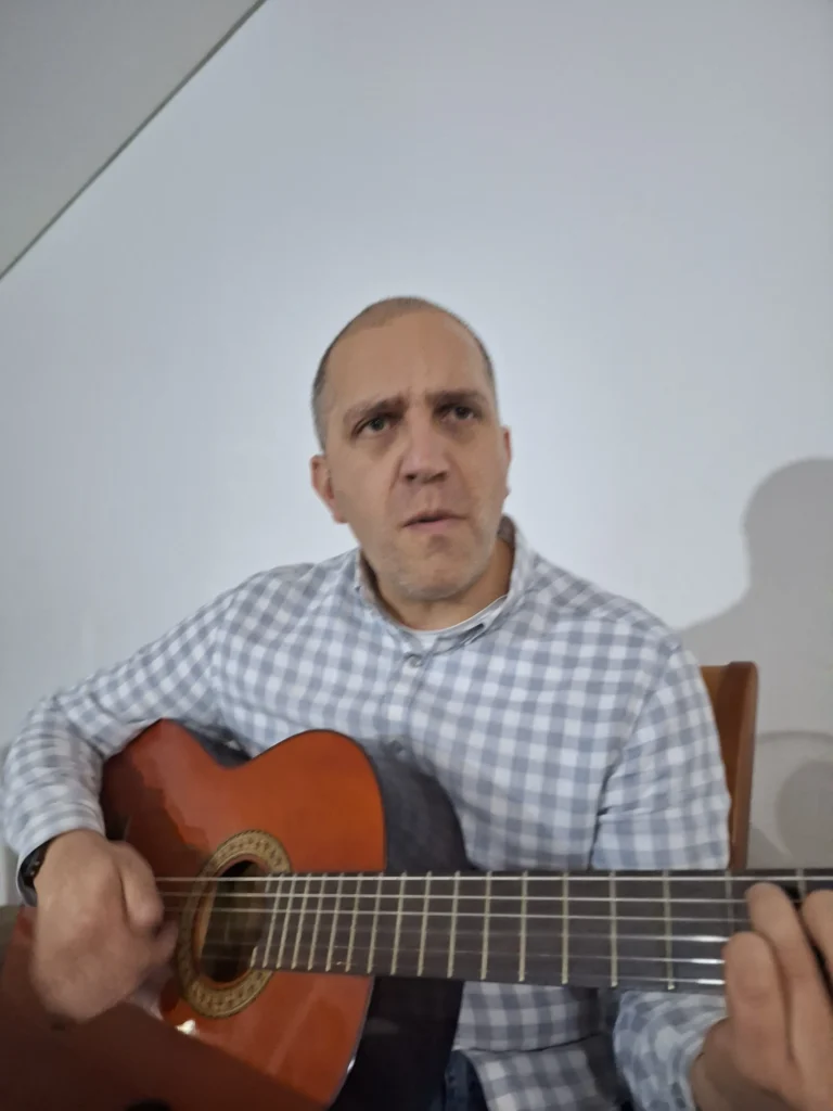 Man concentrating hard while playing guitar in a checkered shirt